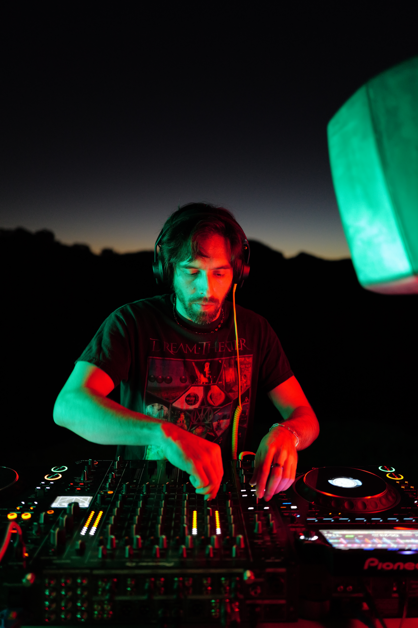 DJ Cano performs at Badcat.fm. Photo shows a DJ handling a DJ deck just after sunset.